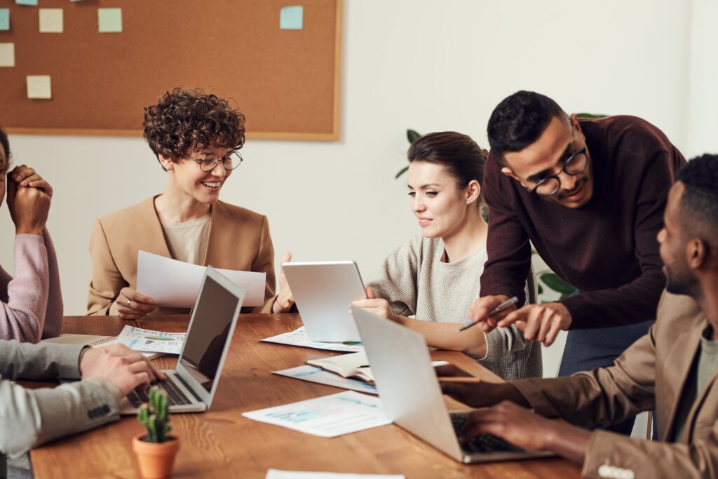 A diverse group of professionals actively engaged in a collaborative team meeting, discussing ideas with laptops and documents on the table.